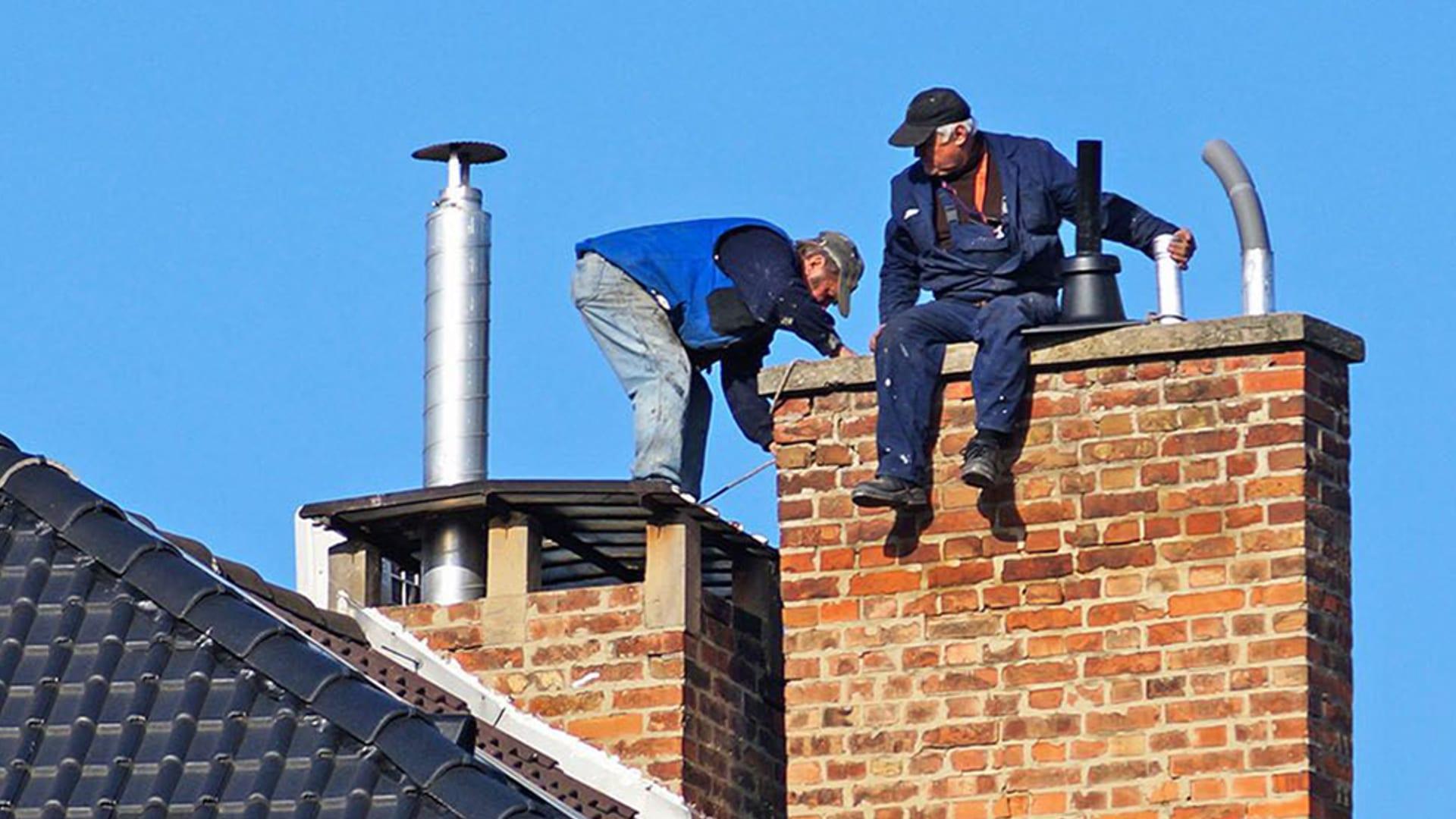 Professional chimney sweep at work on a rooftop